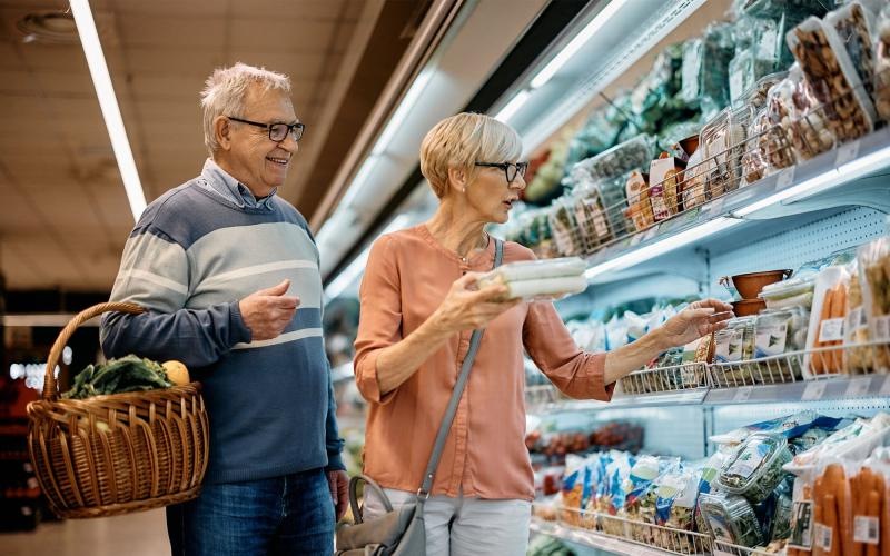 a man and woman looking at a book in a grocery store