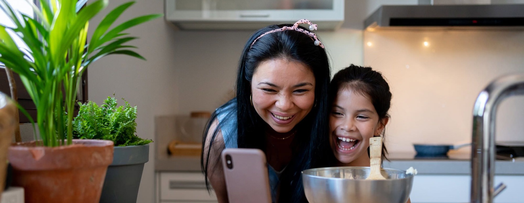 a mom and child looking at a phone in a bright kitchen